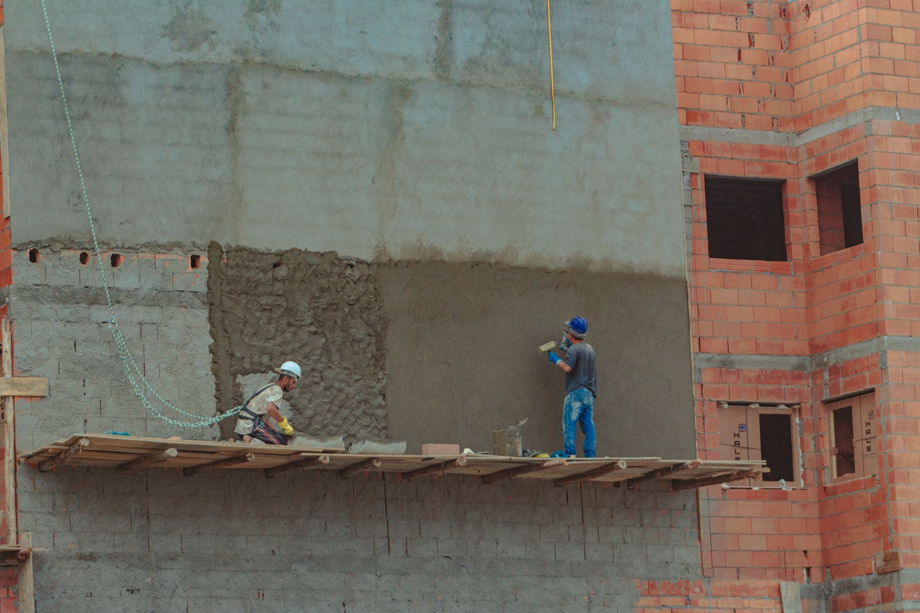 Workers beside an unfinished brick wall